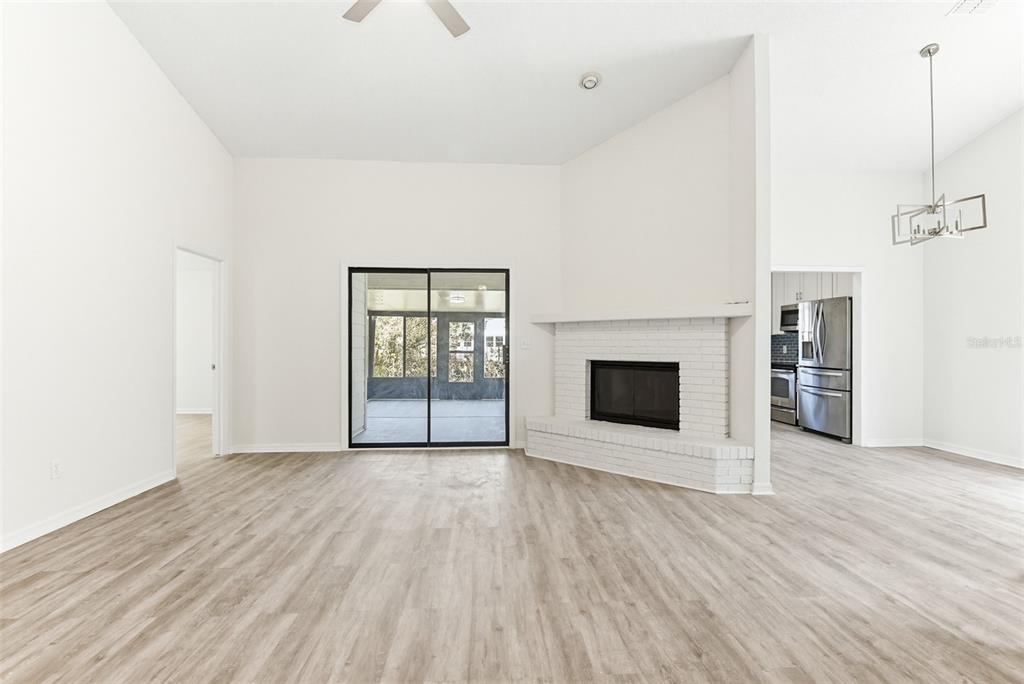 A living room features light wood-look flooring, a white brick fireplace, and sliding glass doors — 756 PINE SHORES CIRCLE, NEW SMYRNA BEACH, FL
