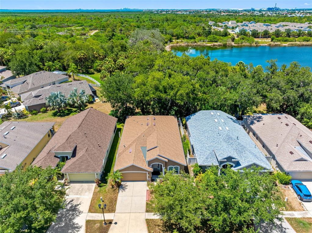 An aerial view shows several suburban houses with shingled roofs near a lake and trees — 5335 CLOVER MIST DRIVE, APOLLO BEACH, FL