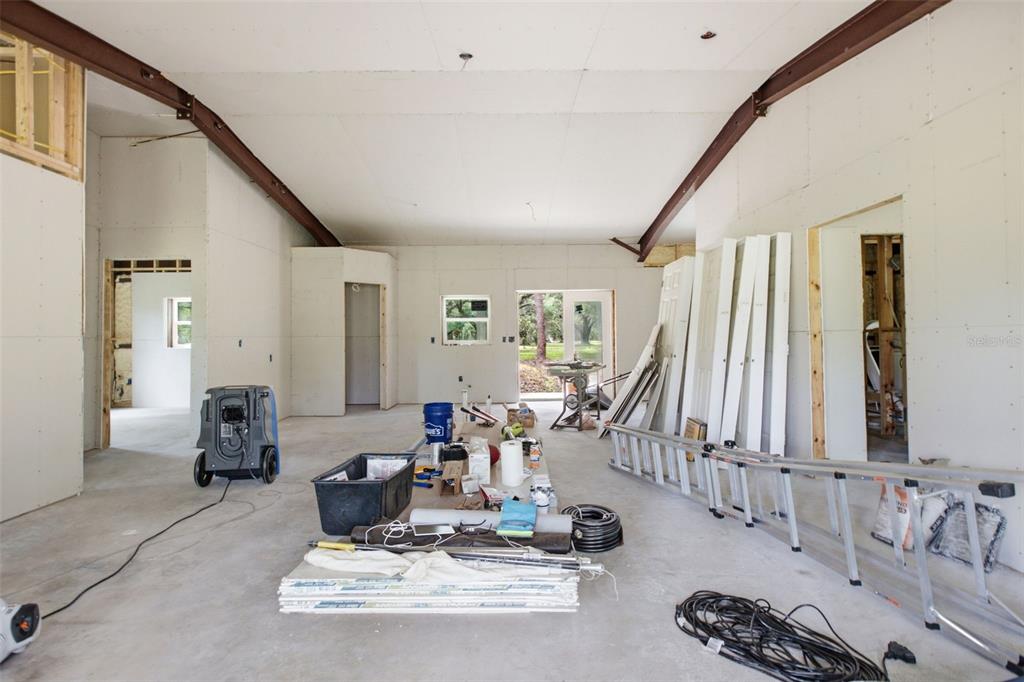 An unfinished interior room features exposed steel beams, drywall walls, and construction materials on the floor — 18127 CEDARHURST ROAD, ORLANDO, FL
