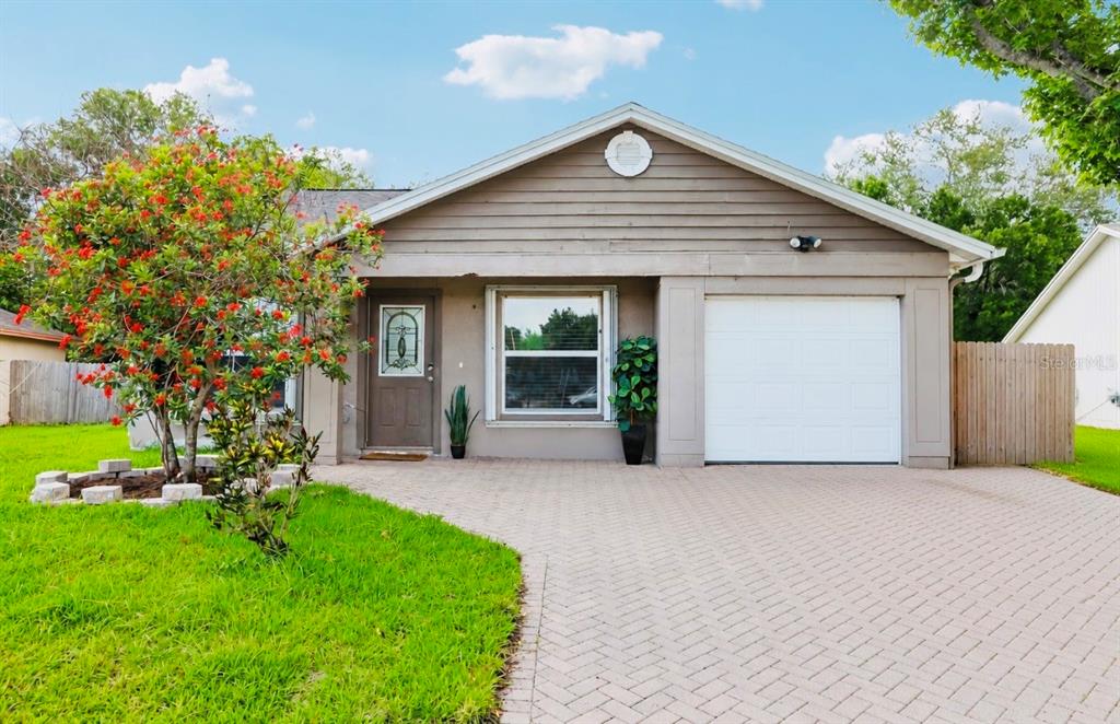 A single-story house with a paved driveway, a garage, and a flowering tree in front — 1525 KESTREL WAY, BRANDON, FL