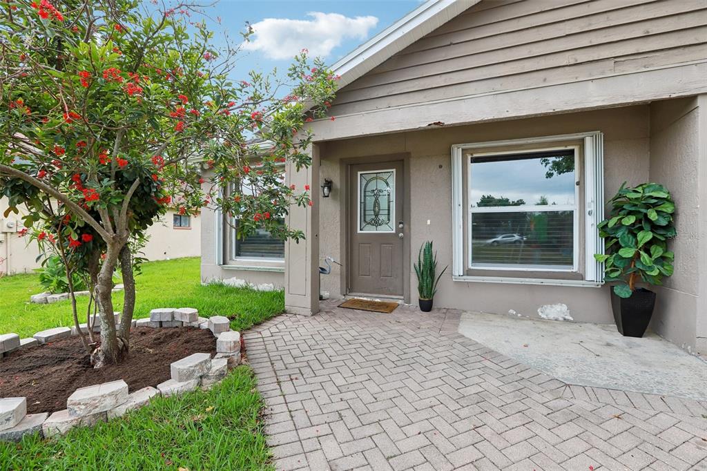 A paved walkway leads to the front entrance of a house with a small tree — 1525 KESTREL WAY, BRANDON, FL