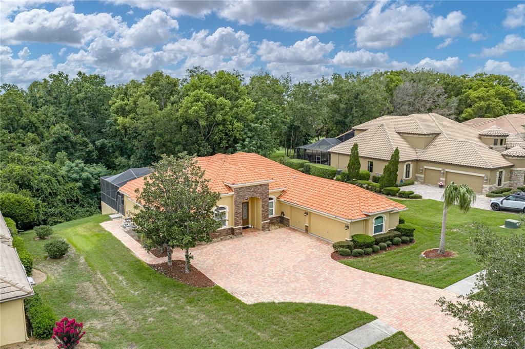 An aerial view of a single-story house with a tile roof and brick paver driveway — 13140 TRADITION DRIVE, DADE CITY, FL