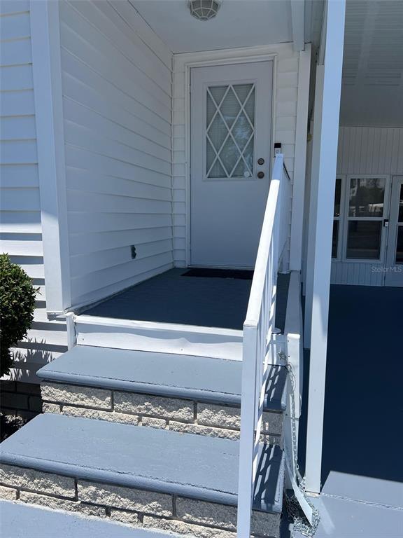 A white front door with a diamond-pattern window sits above concrete steps and a porch — 351 KING PALM STREET, LARGO, FL