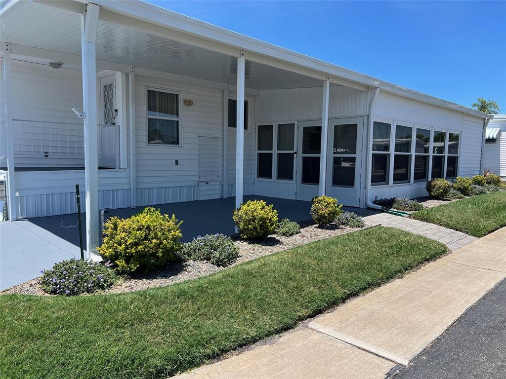 A white mobile home features a covered patio, a screened-in porch, and landscaped front yard — 351 KING PALM STREET, LARGO, FL