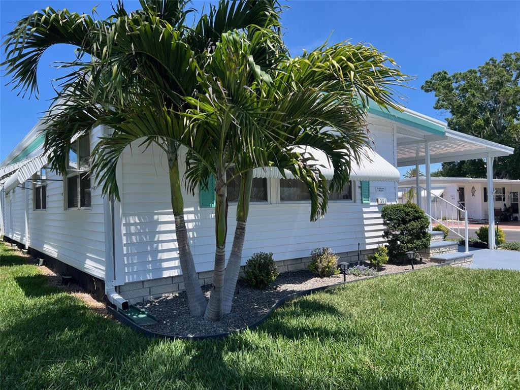A white mobile home features a palm tree in the front yard and a carport — 351 KING PALM STREET, LARGO, FL