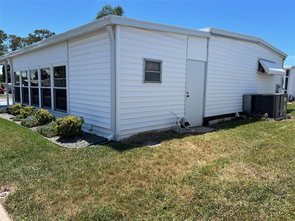The exterior of a white mobile home features a side door, windows, and an air conditioner — 351 KING PALM STREET, LARGO, FL