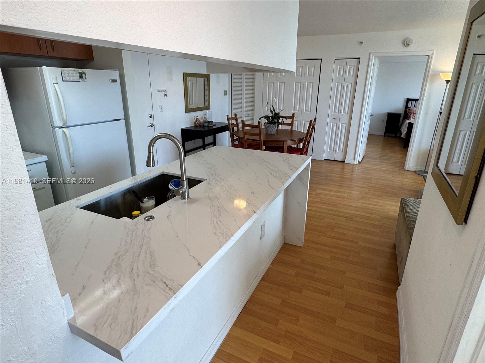 A kitchen features a marble-patterned island with a stainless steel sink and wood flooring — 816 NW 11th St # 1108, Miami FL 33136, MIAMI, FL