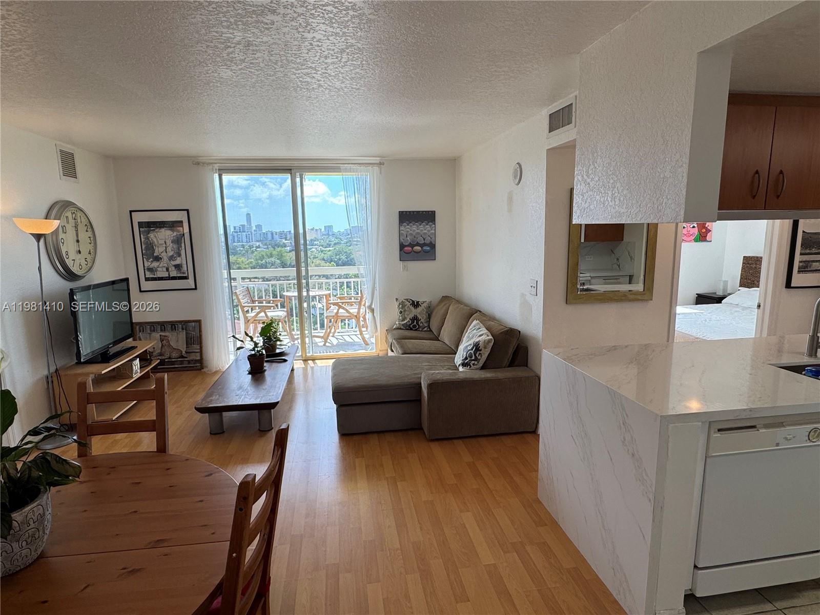 A living room with wood flooring, a sectional sofa, and a balcony overlooking a city — 816 NW 11th St # 1108, Miami FL 33136, MIAMI, FL
