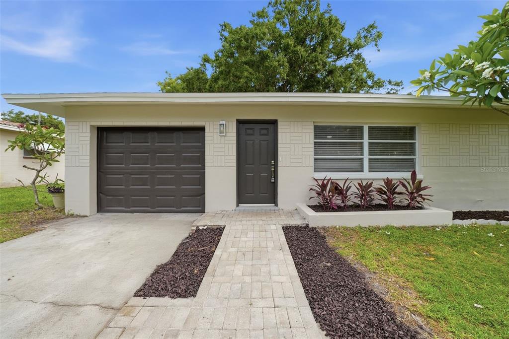 A single-story house exterior features a garage, a dark front door, and a brick walkway — 11325 110TH AVENUE, LARGO, FL
