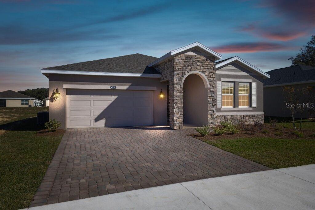 A single-story suburban house features a stone-accented entryway, a two-car garage, and a paved driveway — 4529 NW 53RD AVENUE ROAD, OCALA, FL