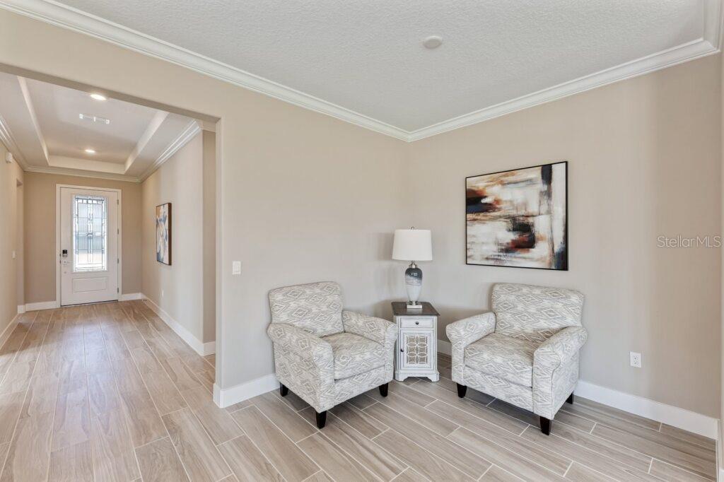 A foyer area features two patterned armchairs, a side table with a lamp, and tile flooring — 4529 NW 53RD AVENUE ROAD, OCALA, FL