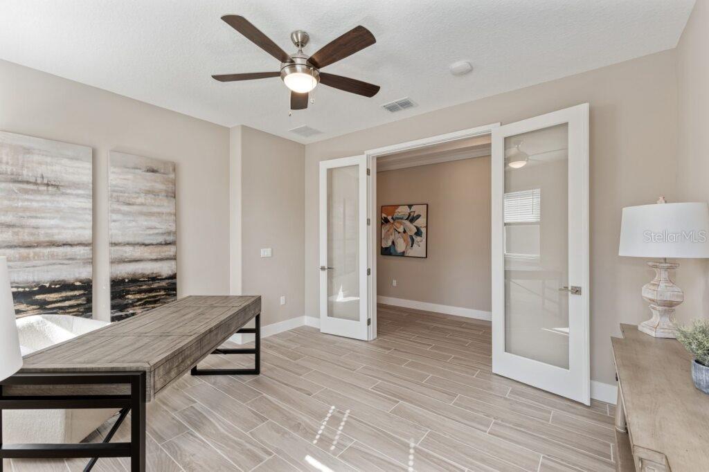 A home office features a wooden desk, tile flooring, and glass-paneled double doors — 4529 NW 53RD AVENUE ROAD, OCALA, FL