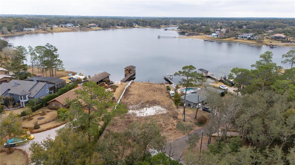 An aerial view shows a vacant waterfront lot situated between two houses and a lake — 601 TUSCANY COURT, SANFORD, FL
