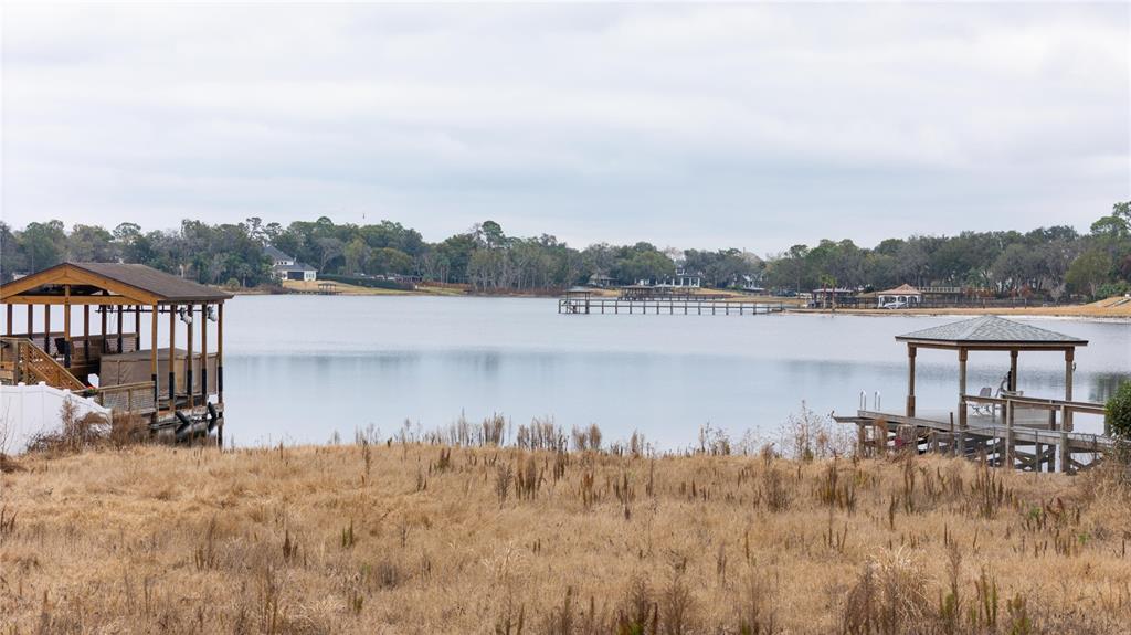 A view of a lake with two wooden boat docks and a grassy shoreline — 601 TUSCANY COURT, SANFORD, FL