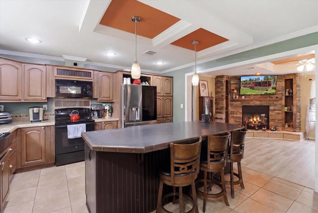 A kitchen with a large island and wood cabinets opens into a living room with fireplace — 1391 S GETTYSBURG DRIVE, HOMOSASSA, FL