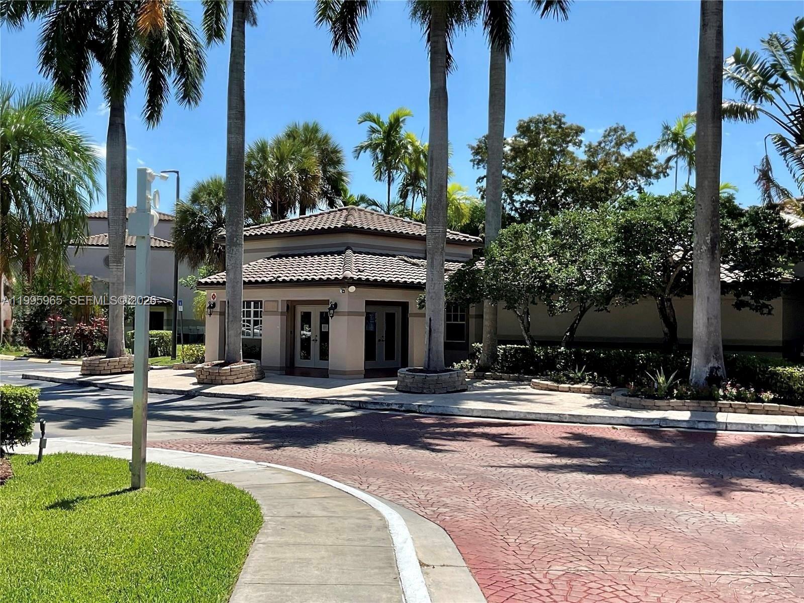 A single-story building with a tiled roof stands surrounded by palm trees and landscaping — 9998 NOB HILL PL # 9998, Sunrise FL 33351, SUNRISE, FL