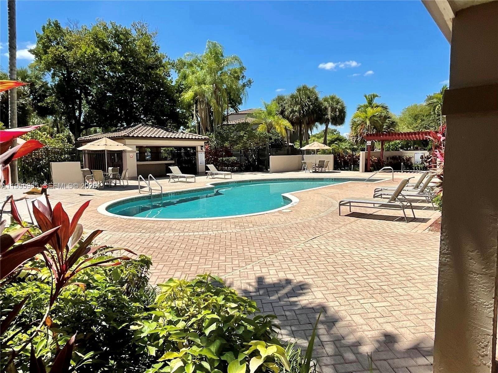 A swimming pool with a surrounding patio, lounge chairs, and a covered pavilion area — 9998 NOB HILL PL # 9998, Sunrise FL 33351, SUNRISE, FL