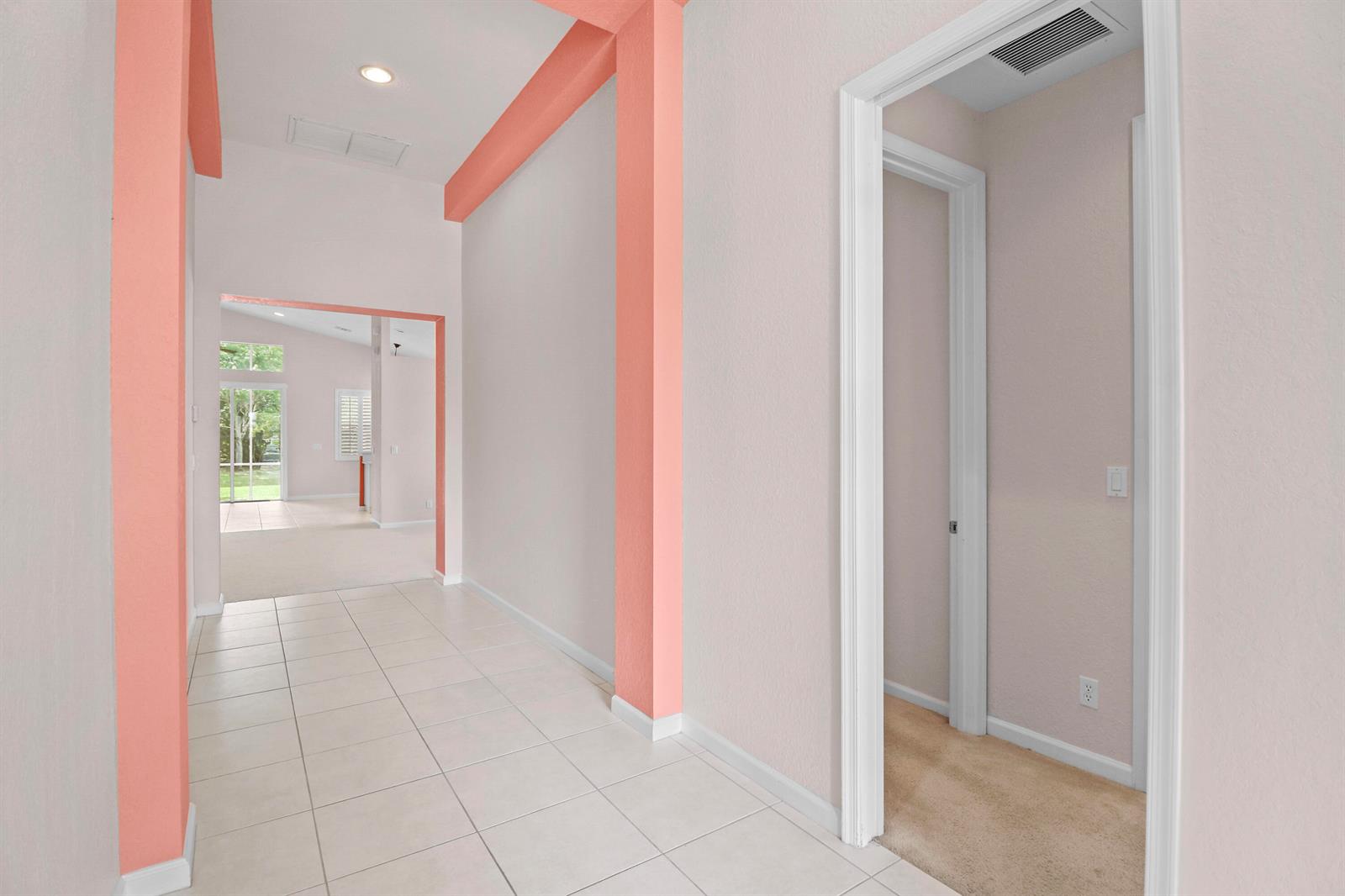A tiled hallway leads to a living area with a view of a screened patio — 1196 SE Fleming Way, Stuart FL 34997, STUART, FL