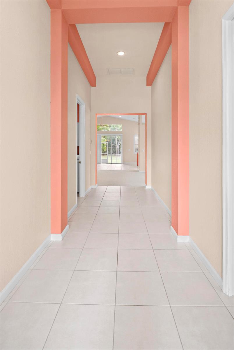 A tiled hallway features peach-colored accent columns and trim leading to an open living area — 1196 SE Fleming Way, Stuart FL 34997, STUART, FL