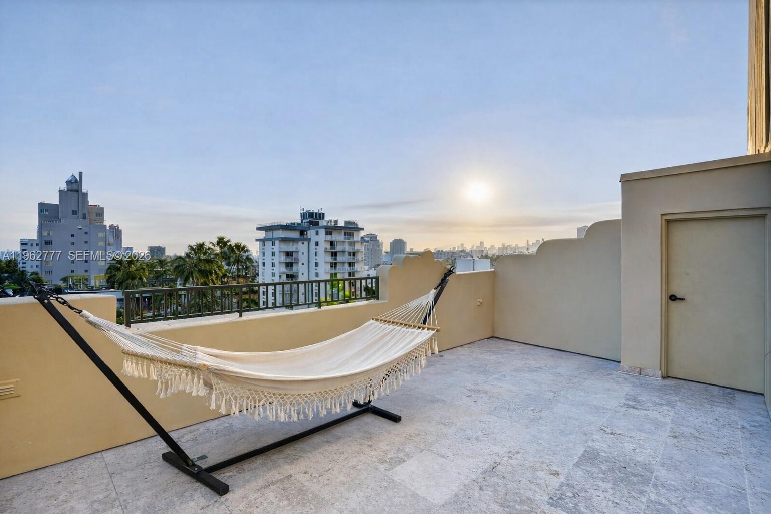 A rooftop terrace features a hammock on a stand, stone flooring, and city skyline views — 1330 Ocean Dr, Miami Beach FL 33139, MIAMI BEACH, FL
