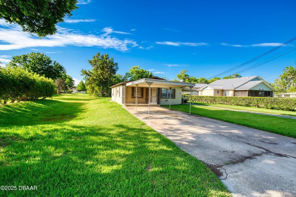 A single-story house with a carport and a concrete driveway sits on a grassy lot — 815 8TH STREET, DAYTONA BEACH, FL