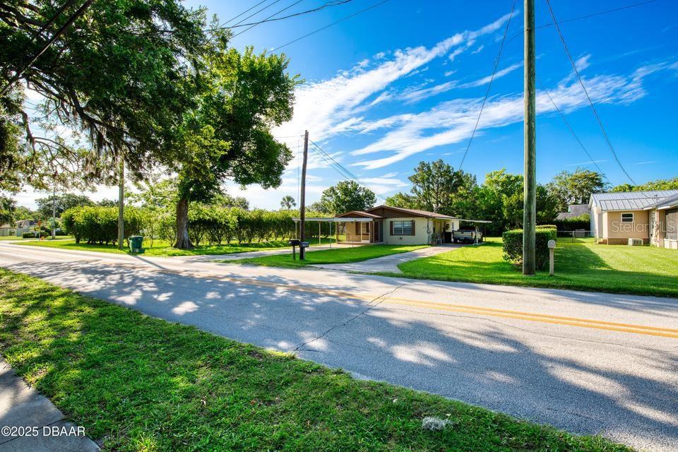 A single-story house with a carport sits on a grassy lot beside a road — 815 8TH STREET, DAYTONA BEACH, FL