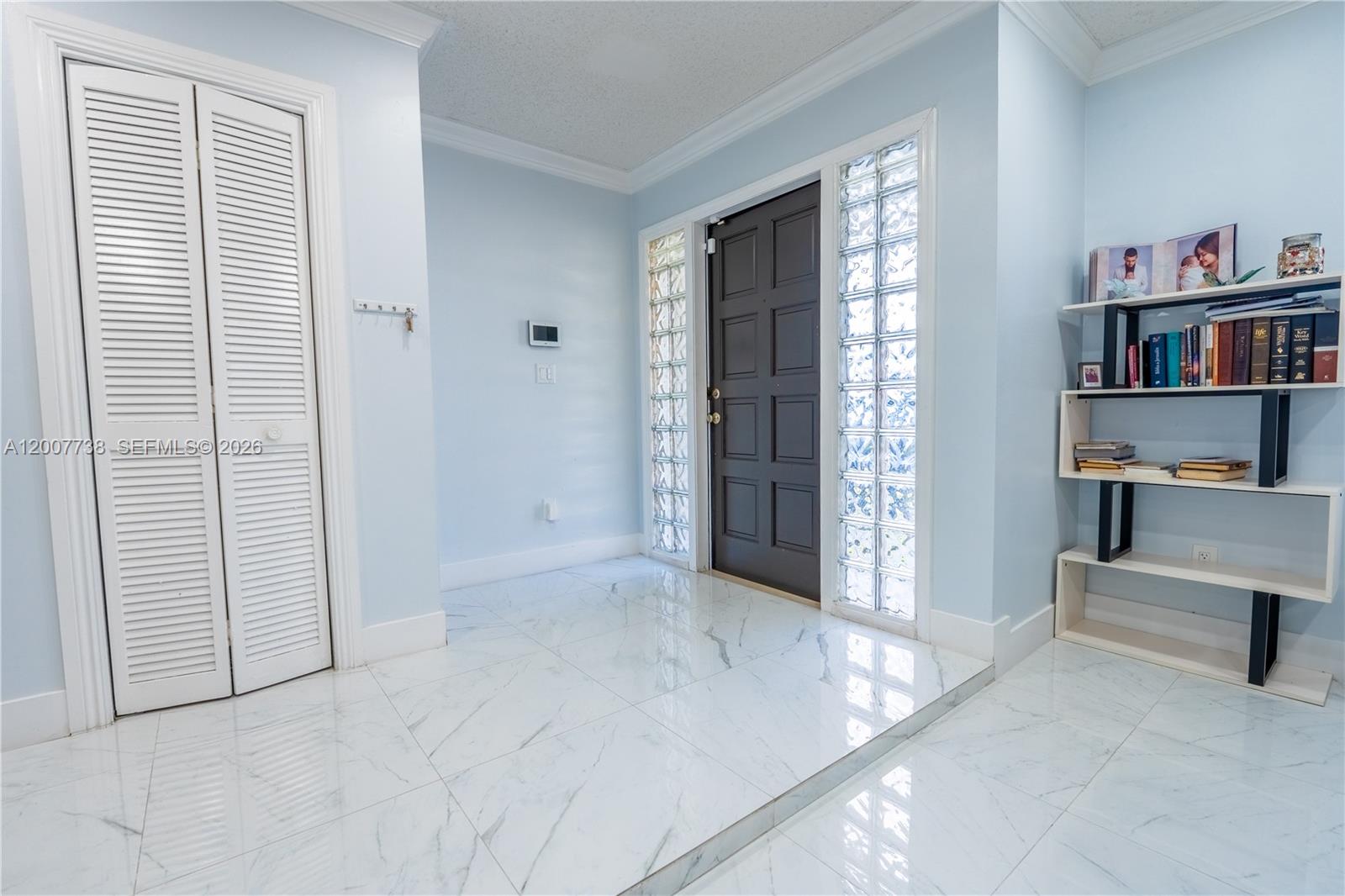 An entryway features light blue walls, white marble-look tile flooring, and a dark front door — 10750 SW 173rd St, Miami FL 33157, MIAMI, FL