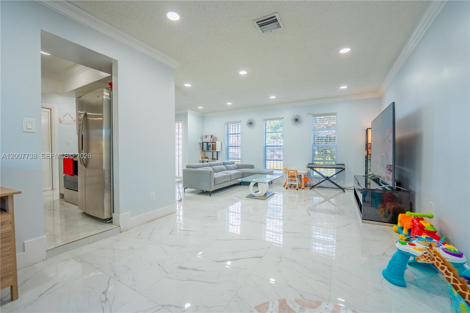 A living room features white marble-look tile flooring, a gray sectional sofa, and recessed lighting — 10750 SW 173rd St, Miami FL 33157, MIAMI, FL