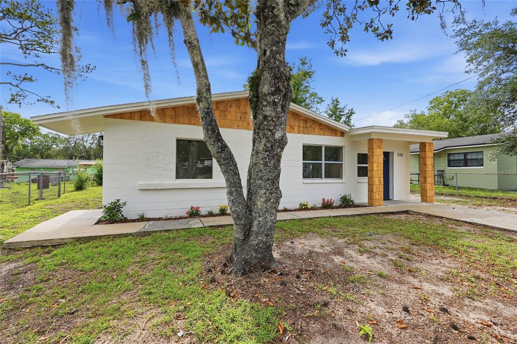 A single-story house with white siding, wood accents, and a covered front porch — 1228 SE 19TH STREET, GAINESVILLE, FL