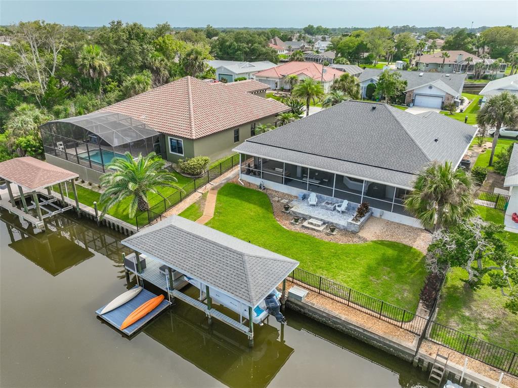 An aerial view shows two waterfront houses with screened lanais, private docks, and boat lifts — 16 CLERMONT COURT, PALM COAST, FL