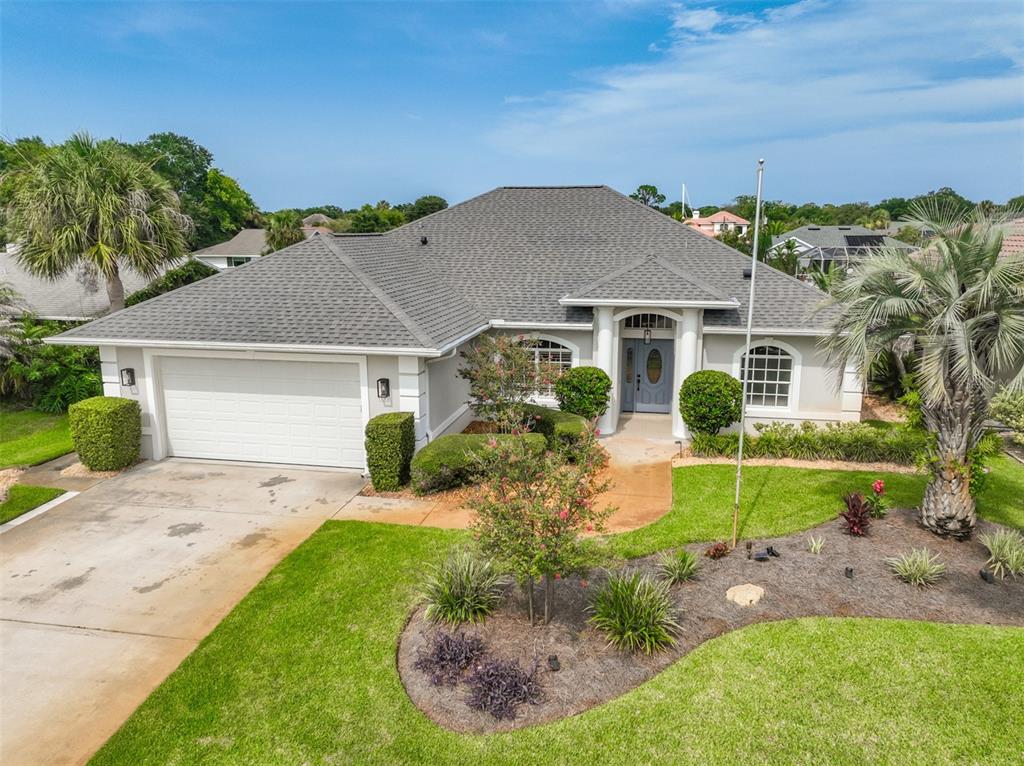 A single-story house with a gray shingled roof, white garage, and landscaped front yard — 16 CLERMONT COURT, PALM COAST, FL