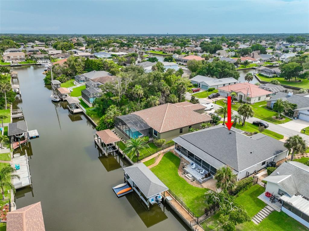 An aerial view shows a waterfront house with a pool, boat dock, and canal — 16 CLERMONT COURT, PALM COAST, FL