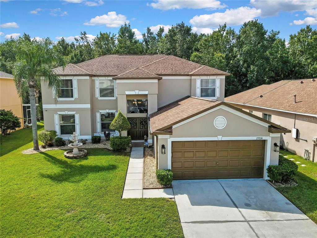 A two-story suburban house with a brown shingle roof, tan stucco siding, and a garage — 25724 FRITH STREET, LAND O LAKES, FL