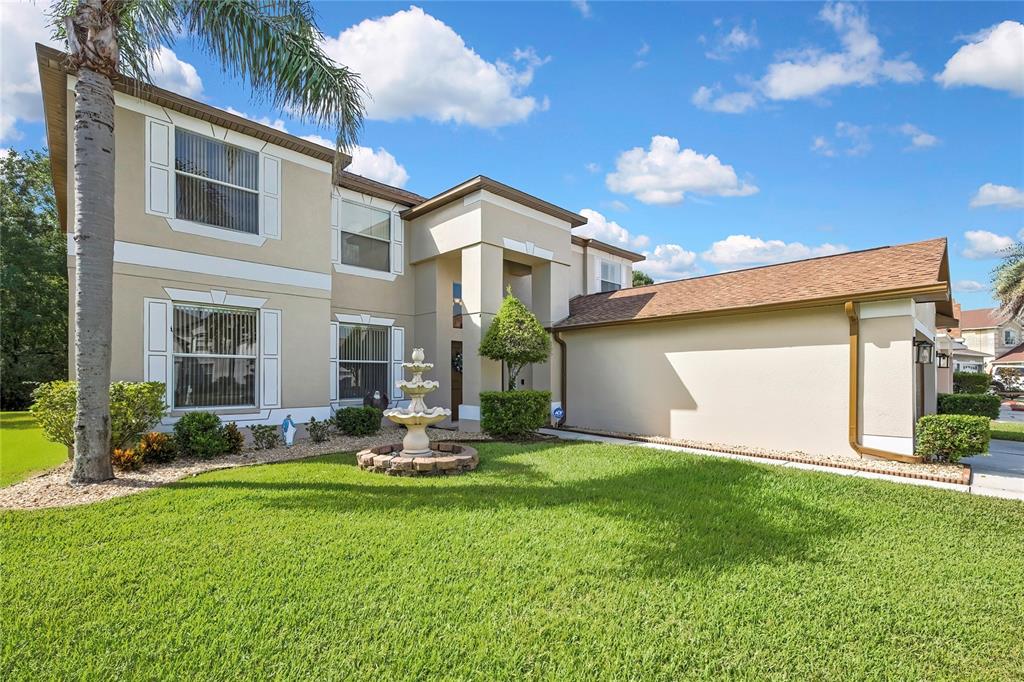A two-story house with a beige stucco exterior, a front fountain, and a palm tree — 25724 FRITH STREET, LAND O LAKES, FL