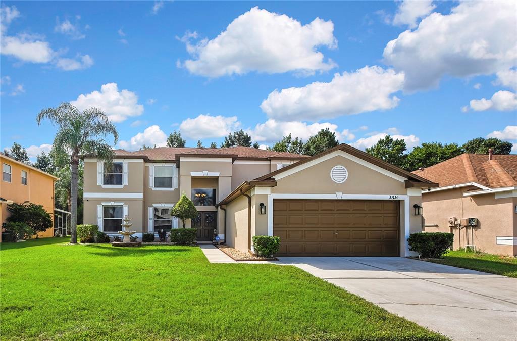 A two-story suburban house with a tan stucco exterior, brown roof, and attached garage — 25724 FRITH STREET, LAND O LAKES, FL