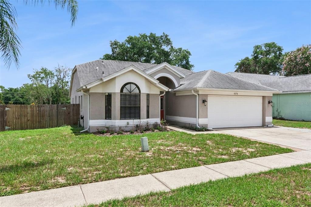 A single-story house with a beige stucco exterior, a two-car garage, and a front lawn — 1574 MARGARETE CRESCENT DRIVE, APOPKA, FL