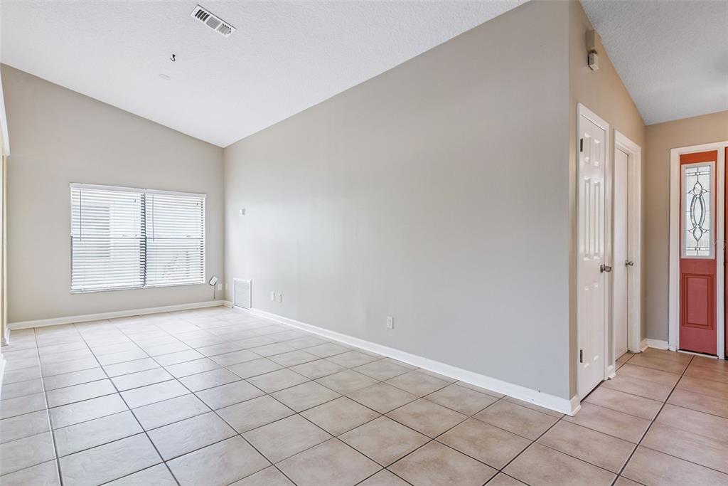 An empty room with beige tile flooring, light gray walls, and a vaulted ceiling — 1574 MARGARETE CRESCENT DRIVE, APOPKA, FL