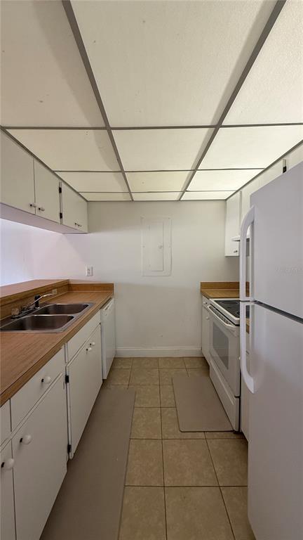A galley kitchen features white cabinets, laminate countertops, a double sink, and a tiled floor — 176 PALM VIEW COURT UNIT 3475/6, HAINES CITY, FL