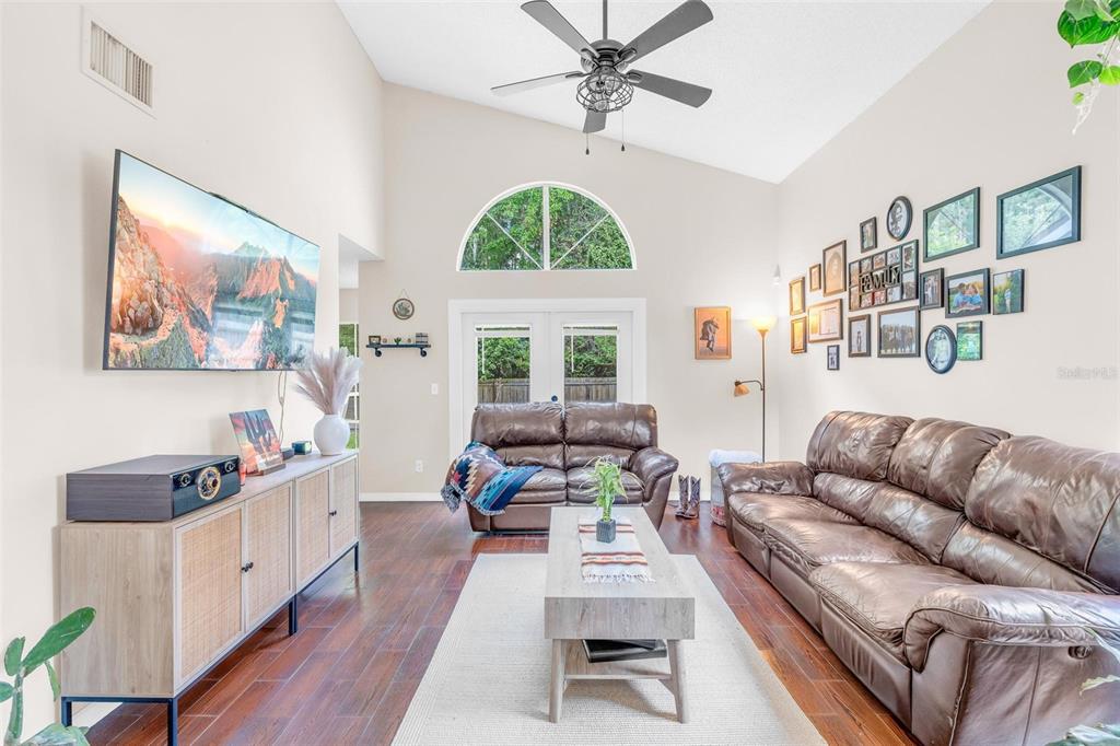 A living room features a vaulted ceiling, brown leather sofas, and a gallery wall — 10561 SATINWOOD CIRCLE, ORLANDO, FL