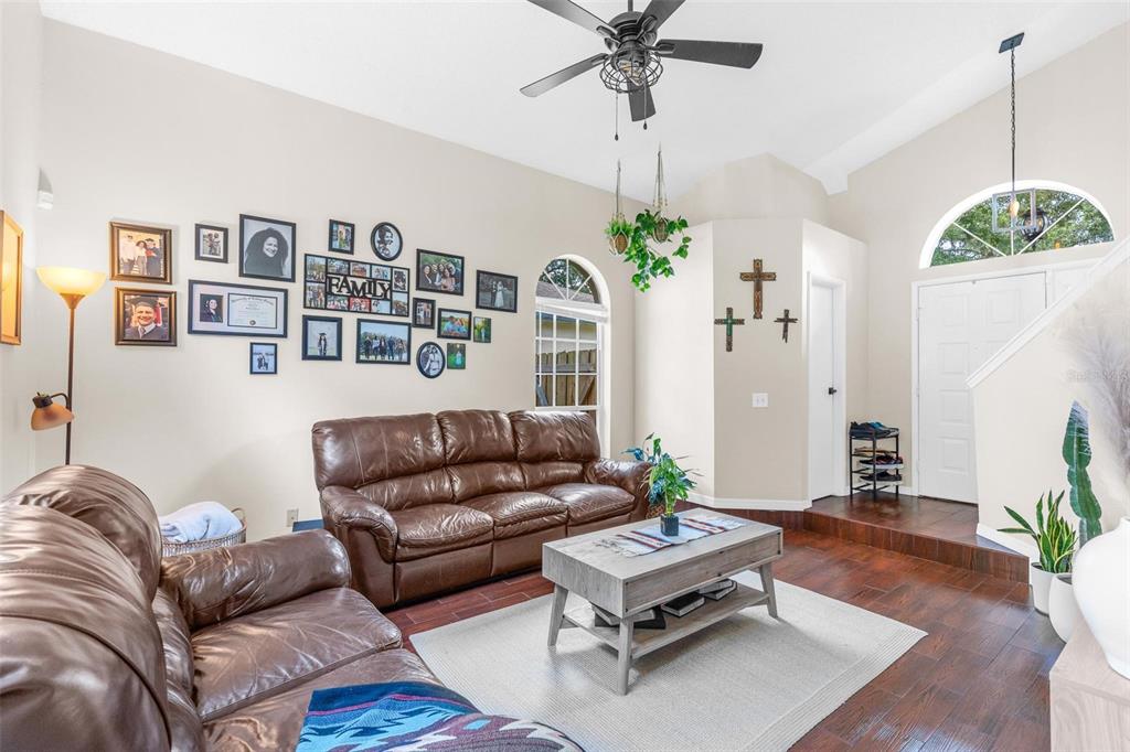 A living room features brown leather sofas, a wood coffee table, and a gallery wall — 10561 SATINWOOD CIRCLE, ORLANDO, FL
