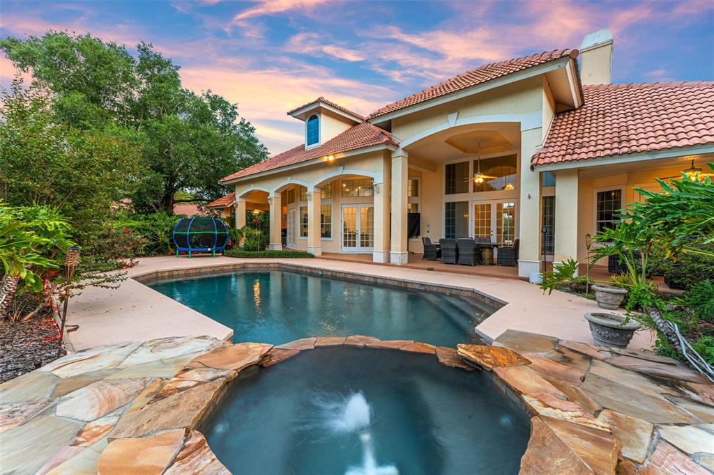 A backyard features a swimming pool, a stone hot tub with a fountain, and a patio — 1274 PRINCE COURT, LAKE MARY, FL