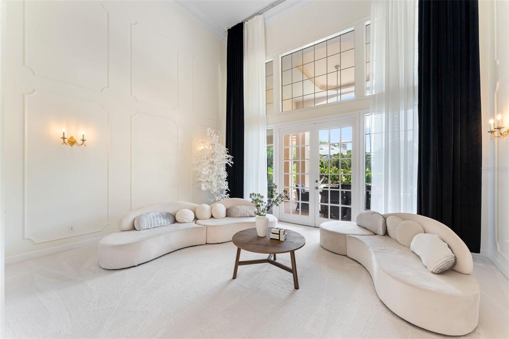 A high-ceilinged living room features two curved cream sofas, a round coffee table, and floor-to-ceiling curtains — 1274 PRINCE COURT, LAKE MARY, FL