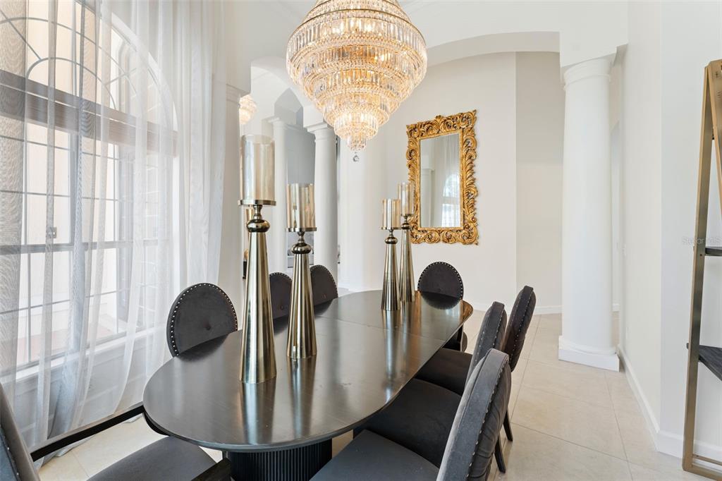 A formal dining room features a dark oval table, gray chairs, and a large crystal chandelier — 1274 PRINCE COURT, LAKE MARY, FL