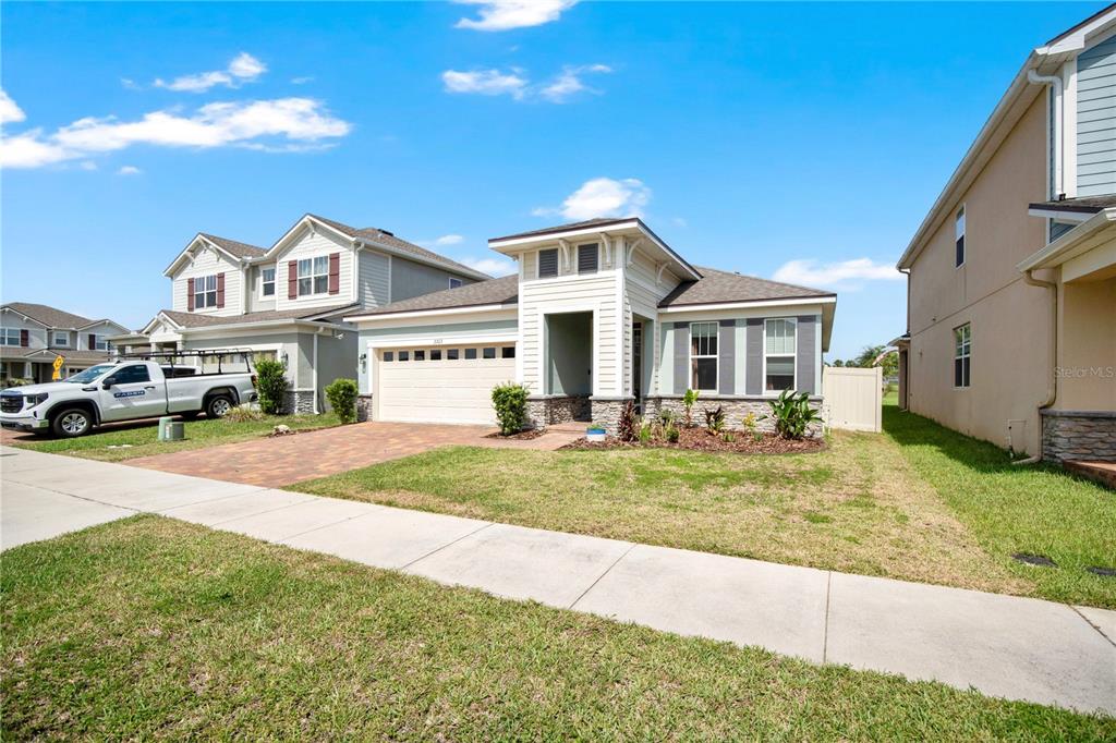 A single-story suburban house with a paved driveway, two-car garage, and a landscaped front yard — 2203 GARDEN BELLE DRIVE, CLERMONT, FL