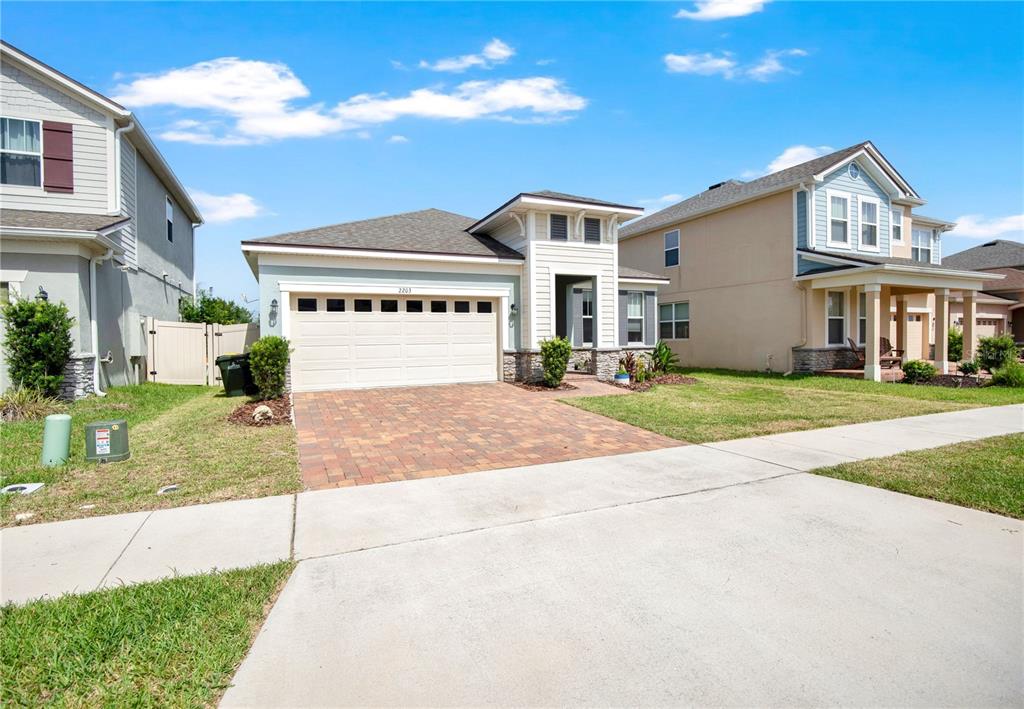 A single-story house with a paved driveway, a two-car garage, and light-colored siding — 2203 GARDEN BELLE DRIVE, CLERMONT, FL