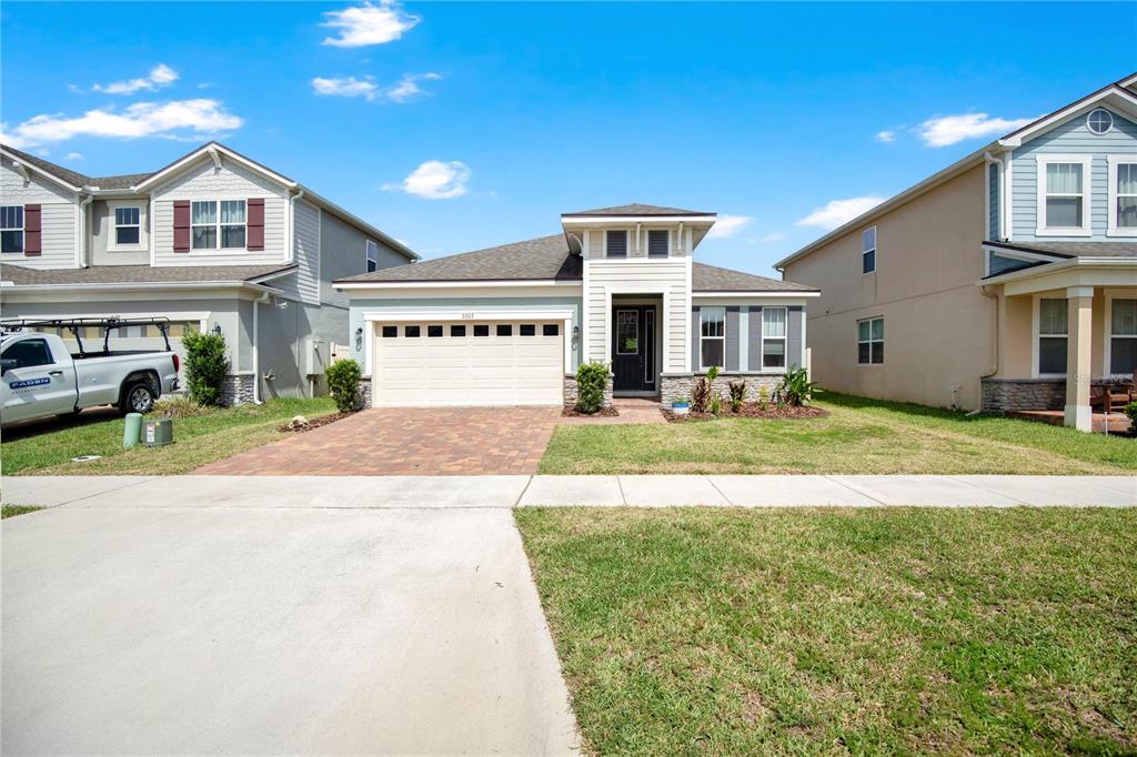 A single-story suburban house with a paved driveway, a two-car garage, and a front entrance — 2203 GARDEN BELLE DRIVE, CLERMONT, FL