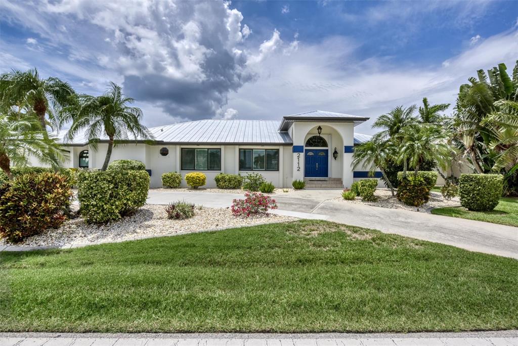 A single-story house with a metal roof, blue double doors, and a landscaped front yard — 2112 DEBORAH DRIVE, PUNTA GORDA, FL