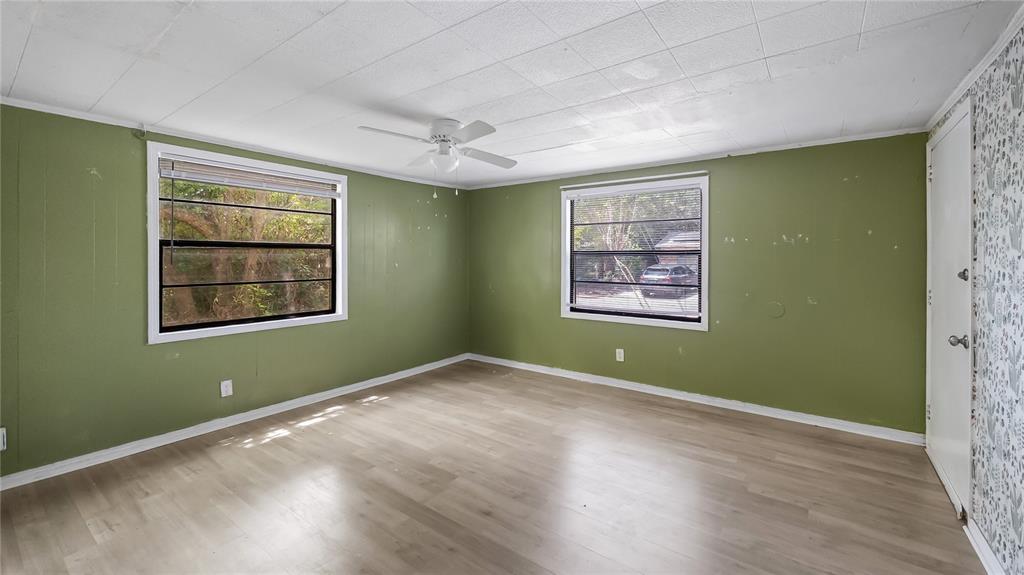 An empty bedroom with olive green walls, light wood-look flooring, and two windows — 2201 DOLARWAY STREET, SANFORD, FL