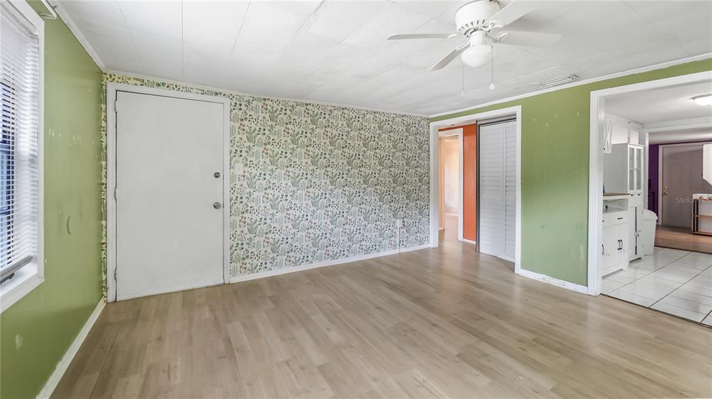 A living room features light wood-look flooring, green walls, and a floral wallpaper accent wall — 2201 DOLARWAY STREET, SANFORD, FL
