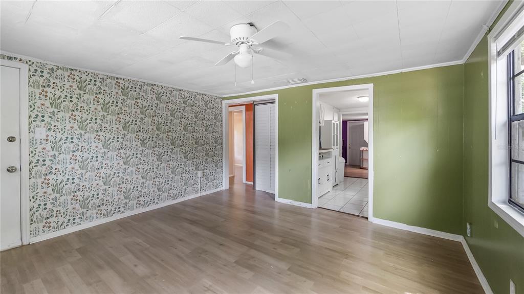 A living room features floral wallpaper, green walls, light wood flooring, and a ceiling fan — 2201 DOLARWAY STREET, SANFORD, FL